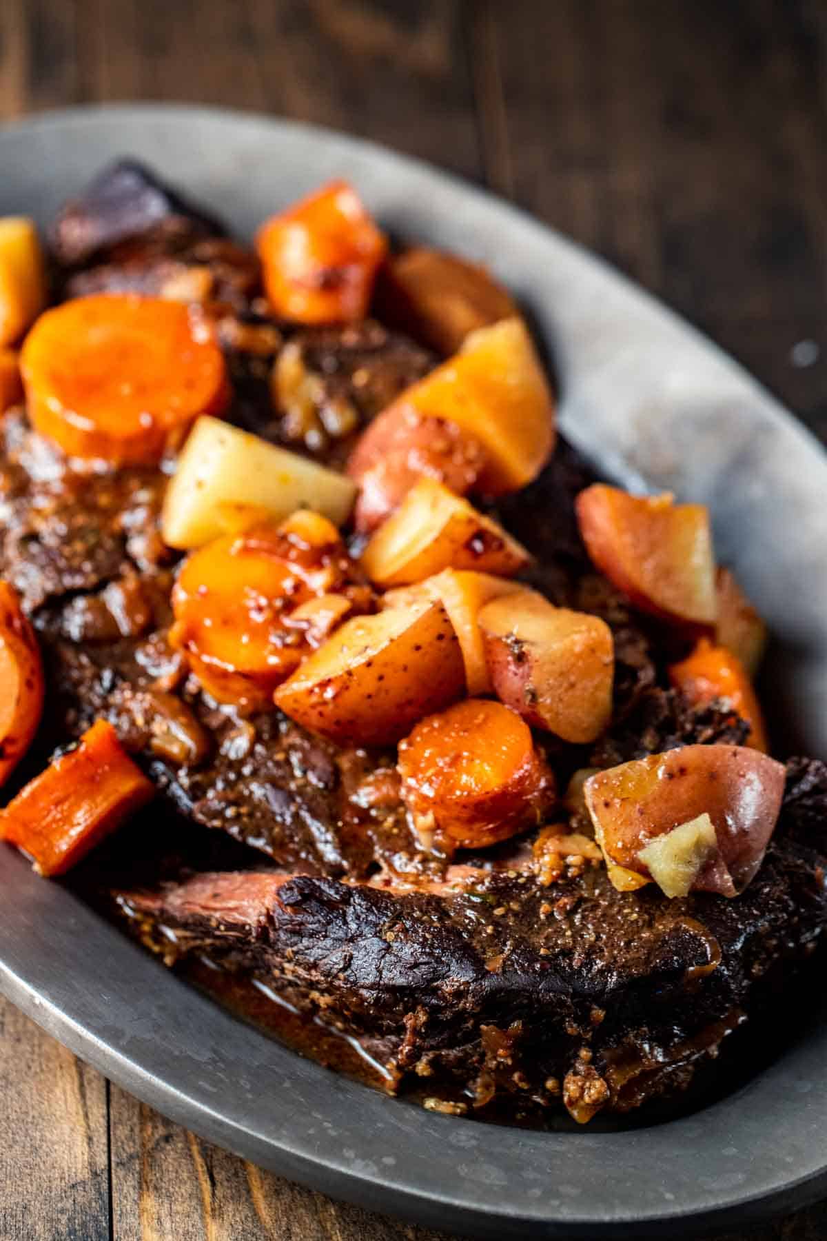 cooked beef with carrots and potatoes on a plate
