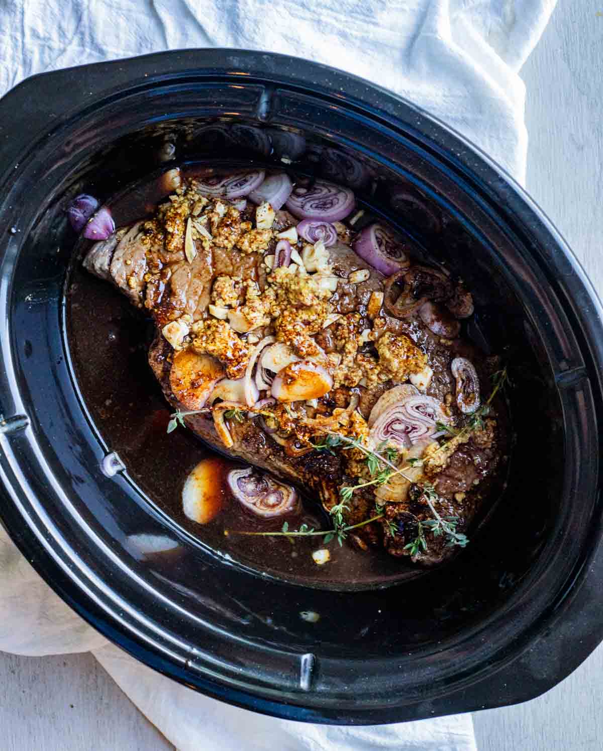 beef in a slow cooker with shallots, sauce and mustard