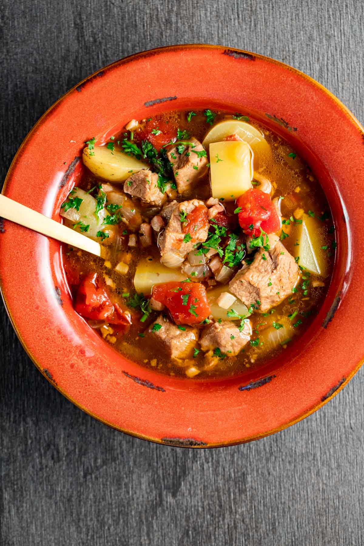 Overhead view of veal stew in a bowl with a spoon inserted into it.