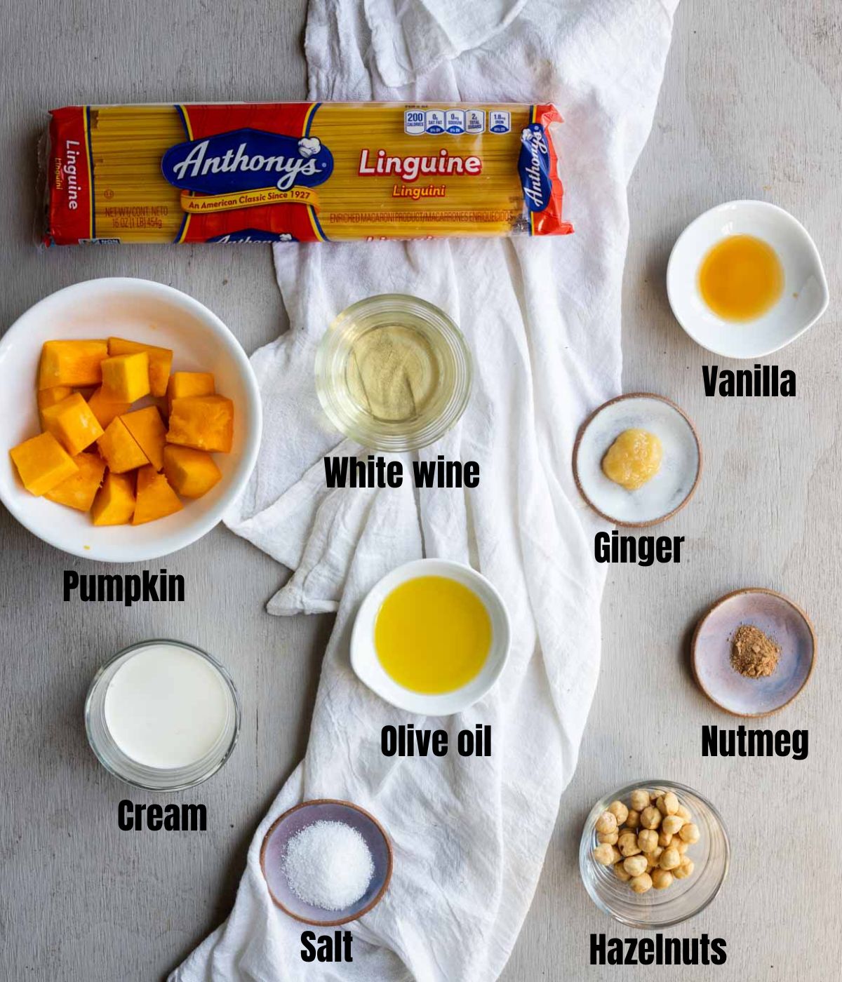 Ingredients to make pumpkin pasta arranged in individual dishes on a grey surface.