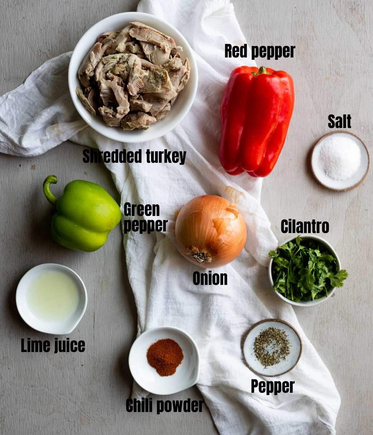 Ingredients to make leftover turkey fajitas arranged individually on a grey surface.