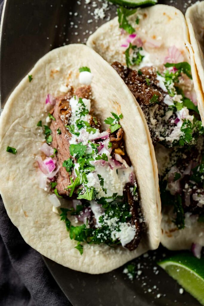 Overhead view of tortillas filled with carne asada and toppings.