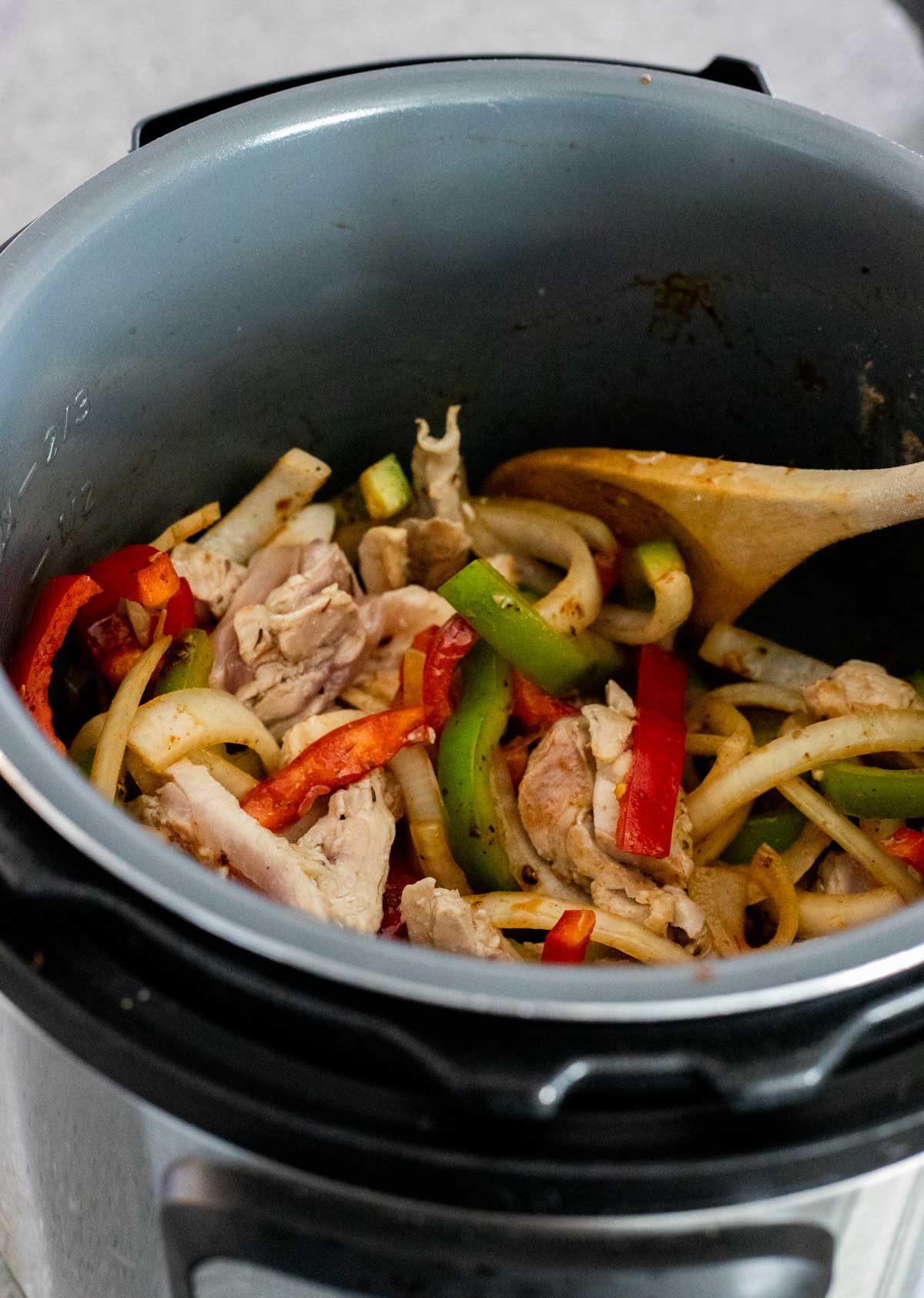 Cooked chicken and cooked slices of peppers and onions in the Instant Pot.