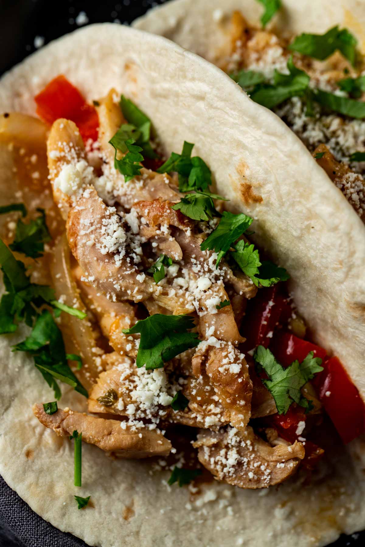 Close up view of a chicken fajita topped with chopped cilantro.