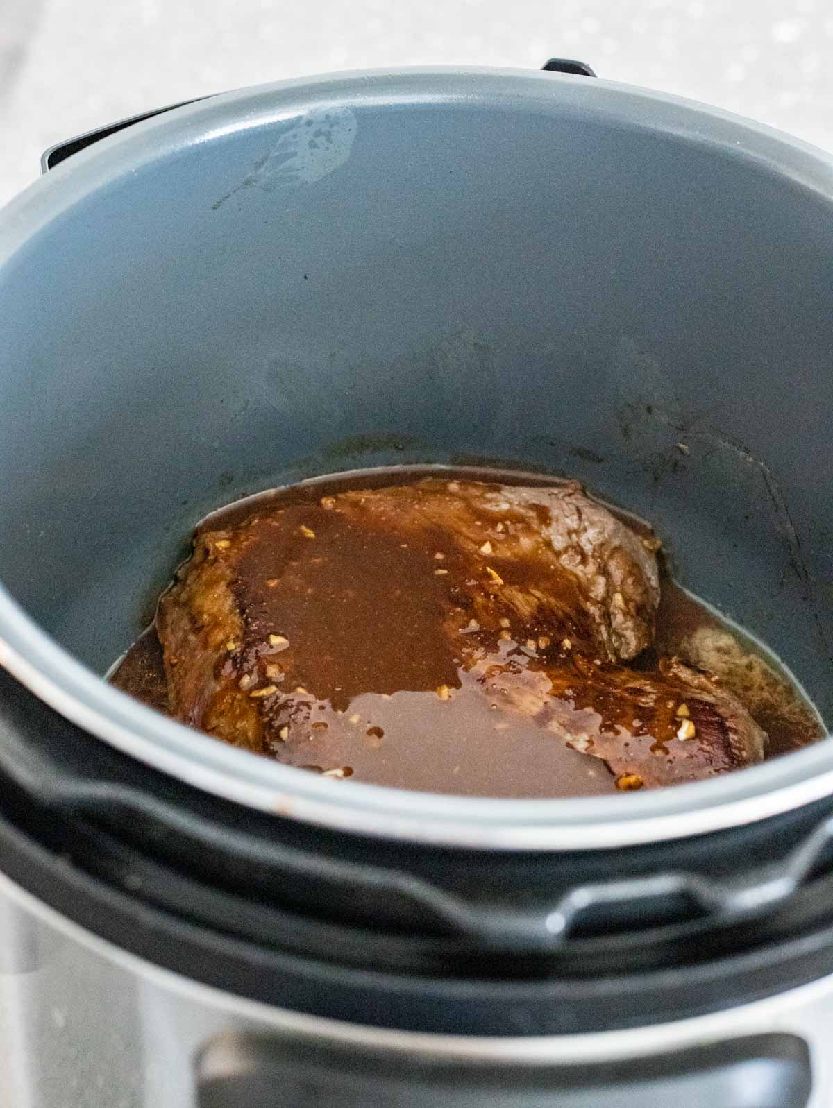 London broil covered with sauce ingredients in the Instant Pot.