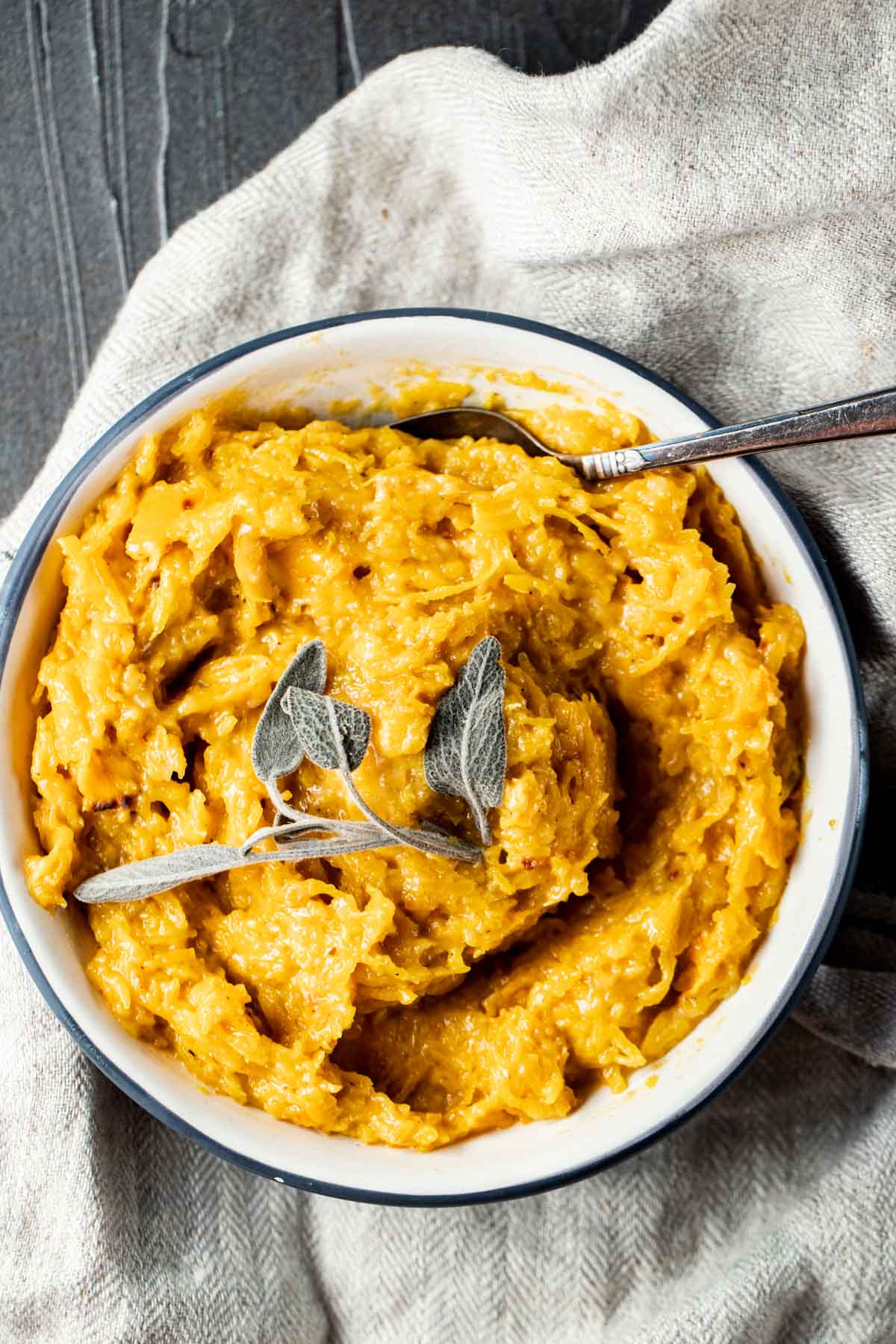 Overhead view of mashed pumpkin in a bowl with a spoon inserted into it.