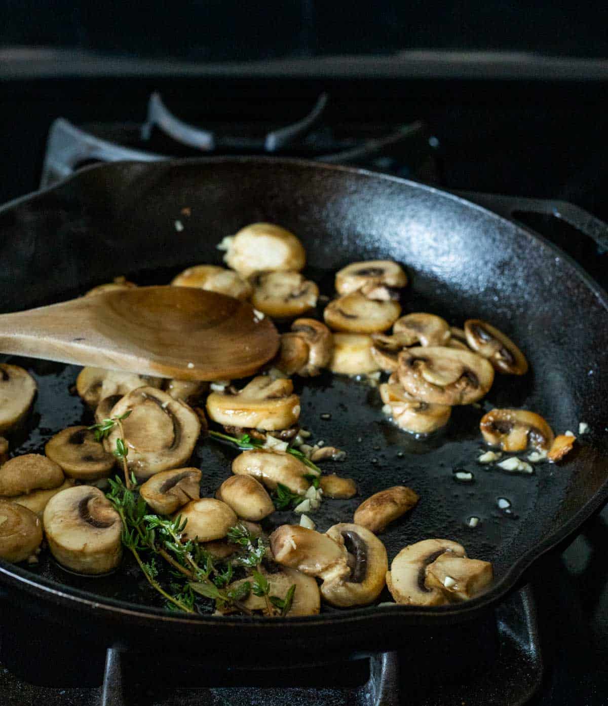 mushrooms cooked in a black pan with a wooden spoon