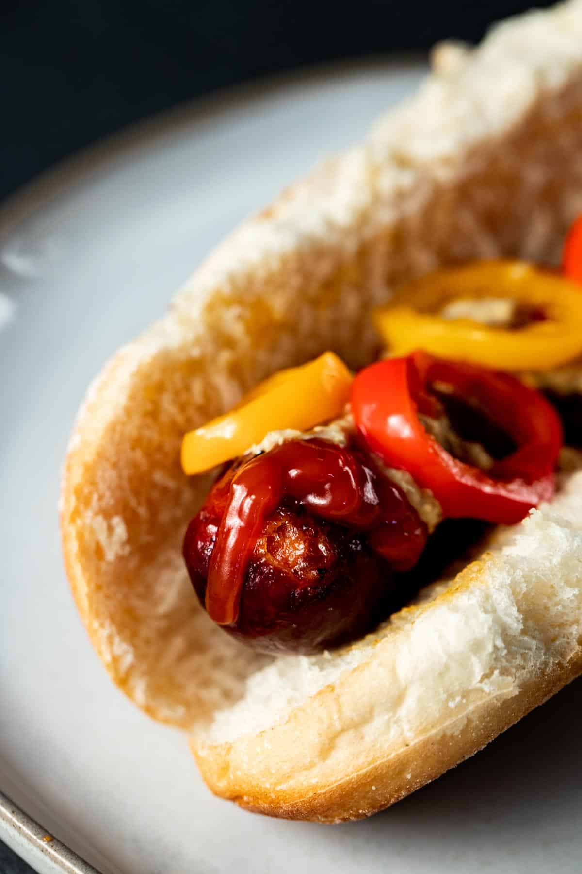 close up view of yellow and red sausages on a white bun