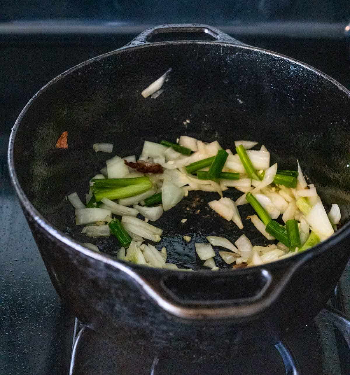 close up view of shallots and onions in a black pan cooking