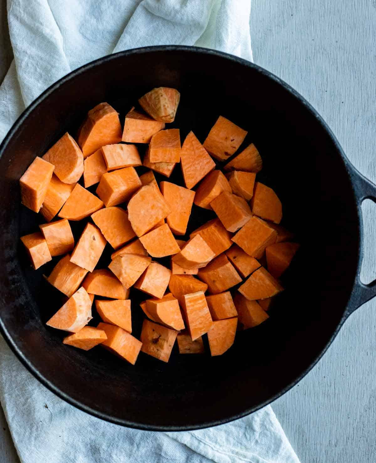 view of sweet potato cut up into cubes in a Dutch Oven