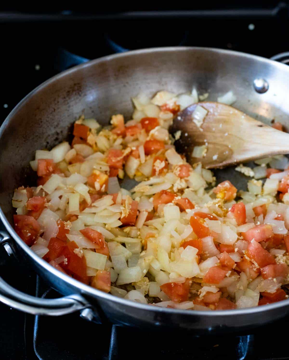 tomatoes and onions sauteing in a pan