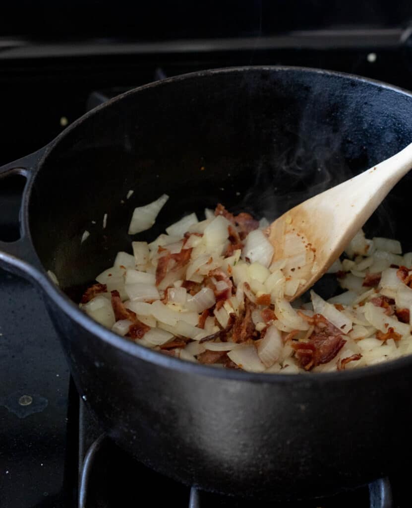 onions in a black pot with a light wooden spoon