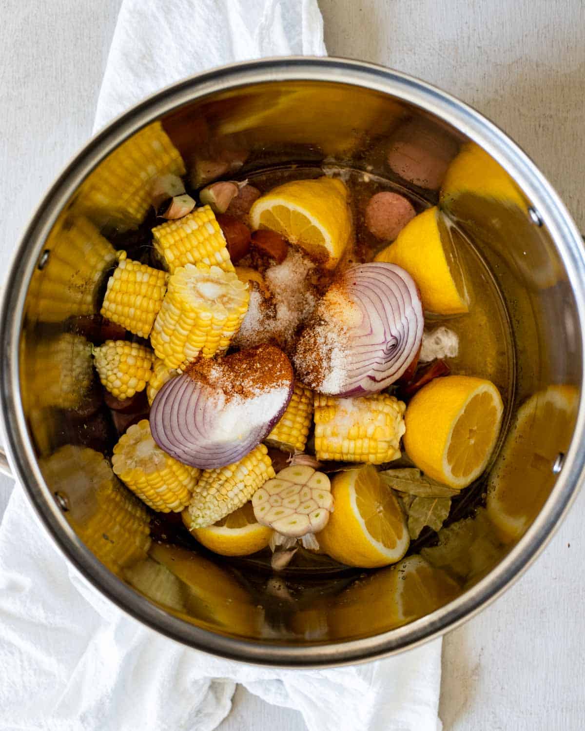 lemons, corn and oniosn in the bottom of a pot