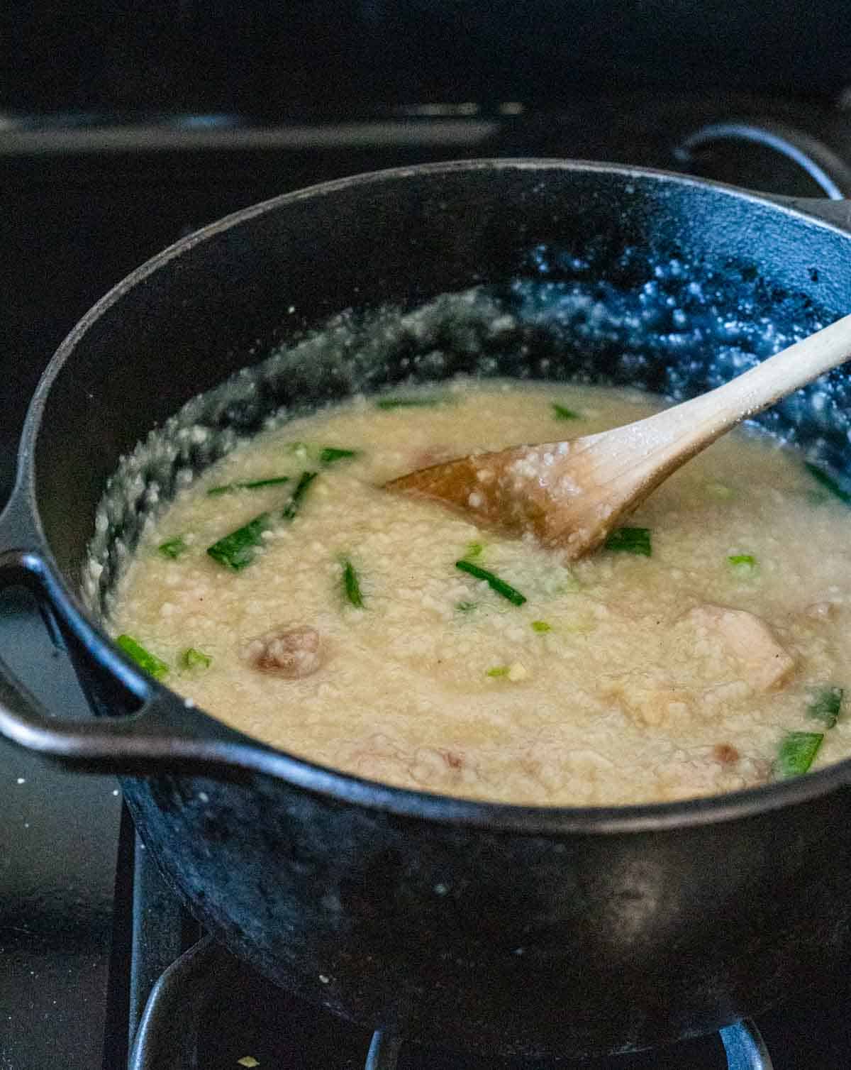 congee with green onions being stirred in a pot
