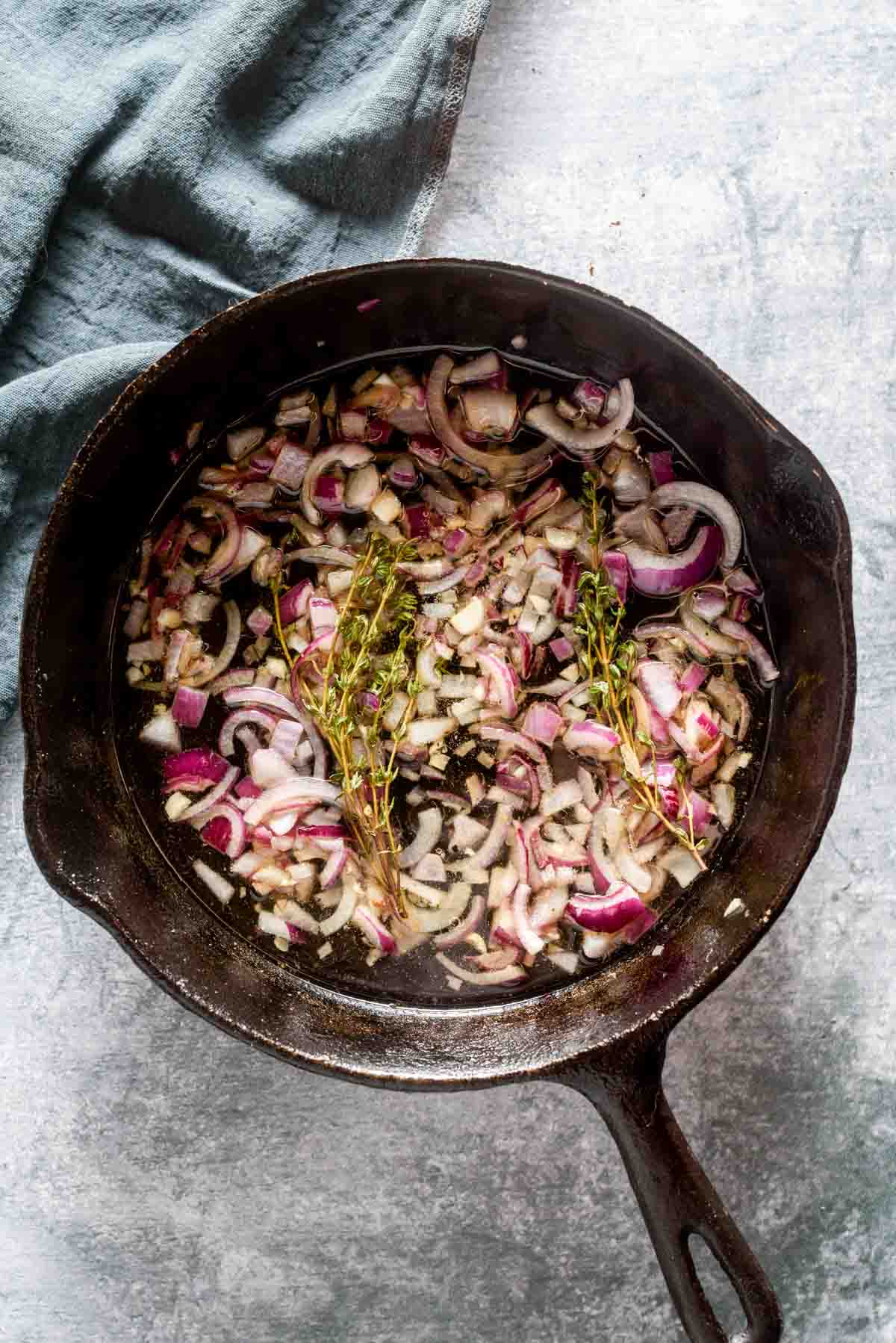 shallots and thyme cooking in a skillet