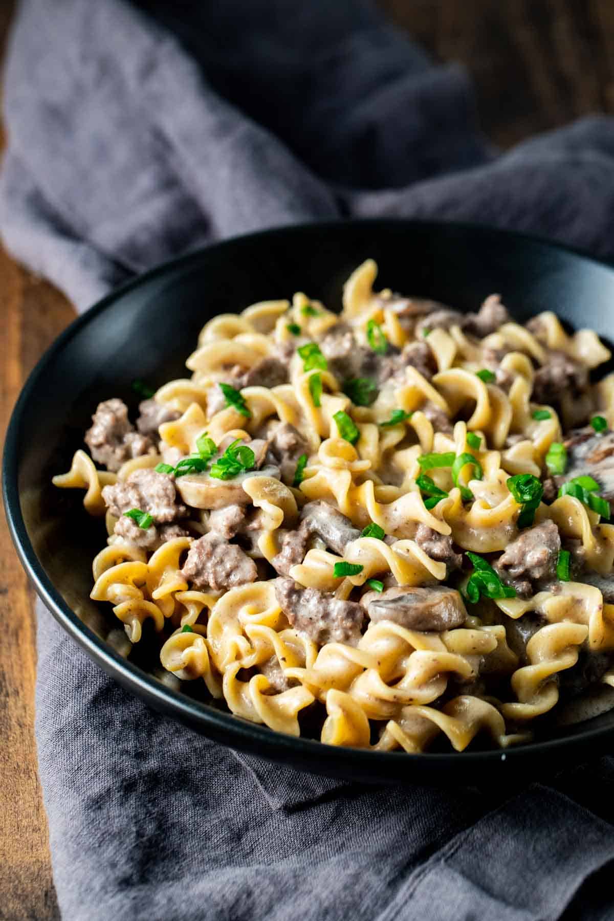 a bowl of creamy beef stroganoff garnished with parsley