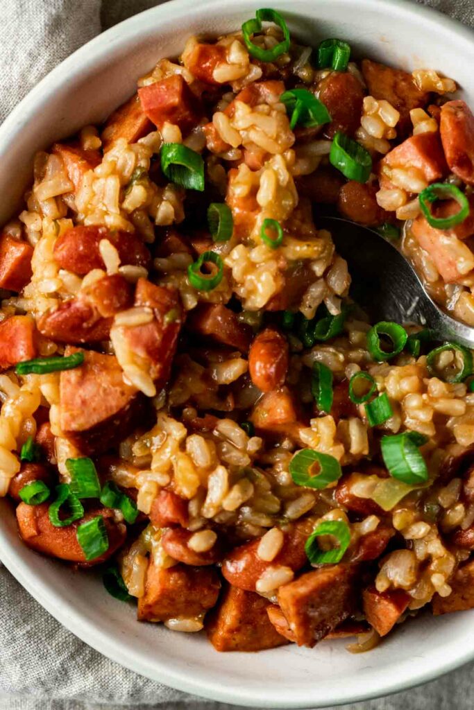 view of red beans and rice in a white bowl with a silver spoon