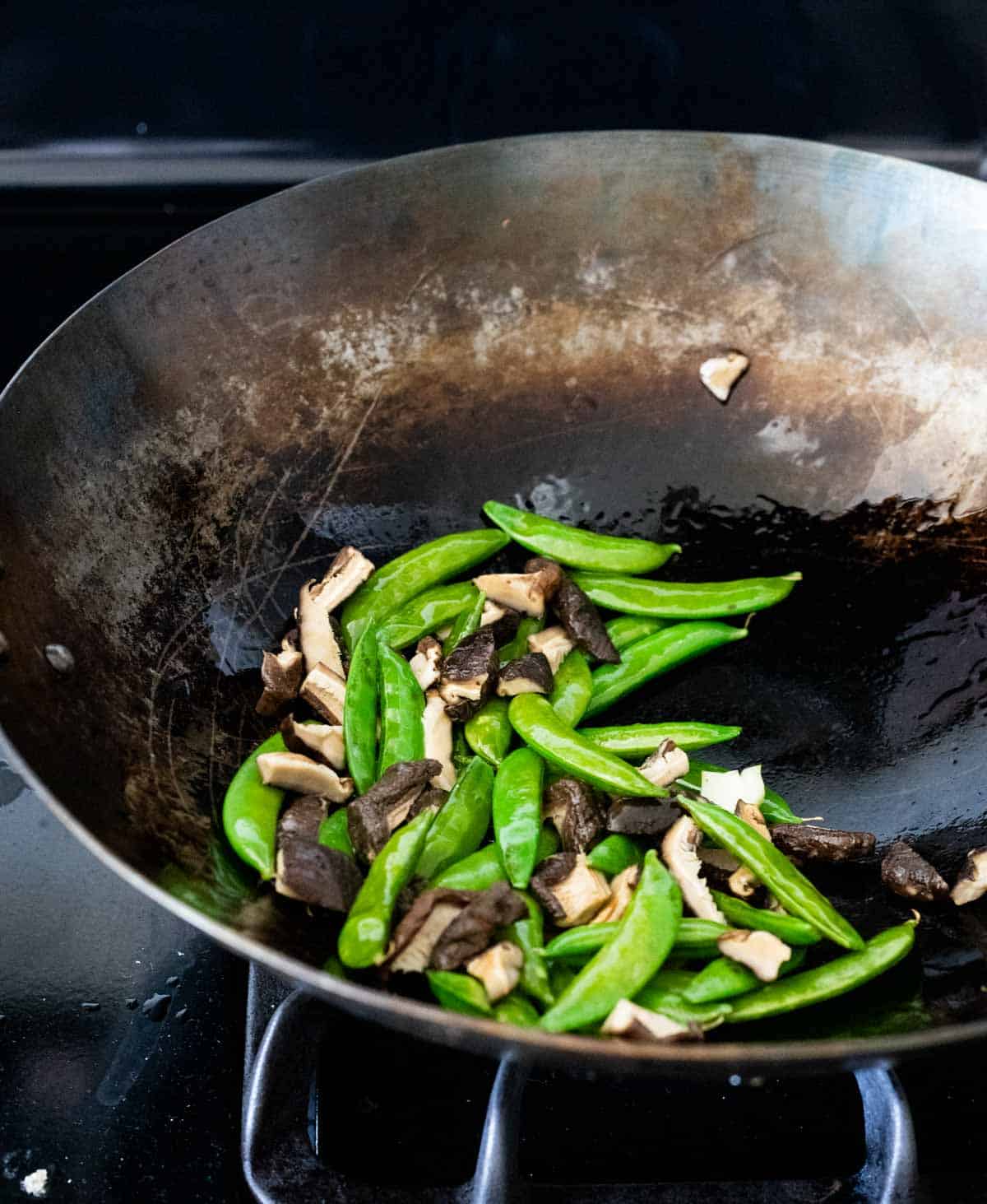 snap peas and mushrooms cooking in a wok