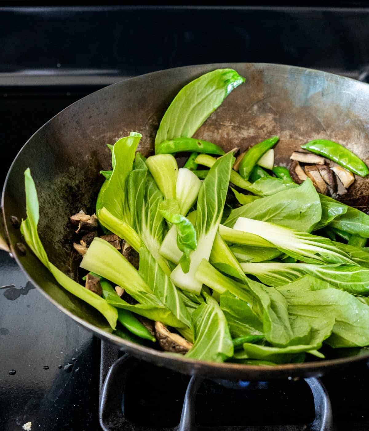 green bok choy cooking in a wok