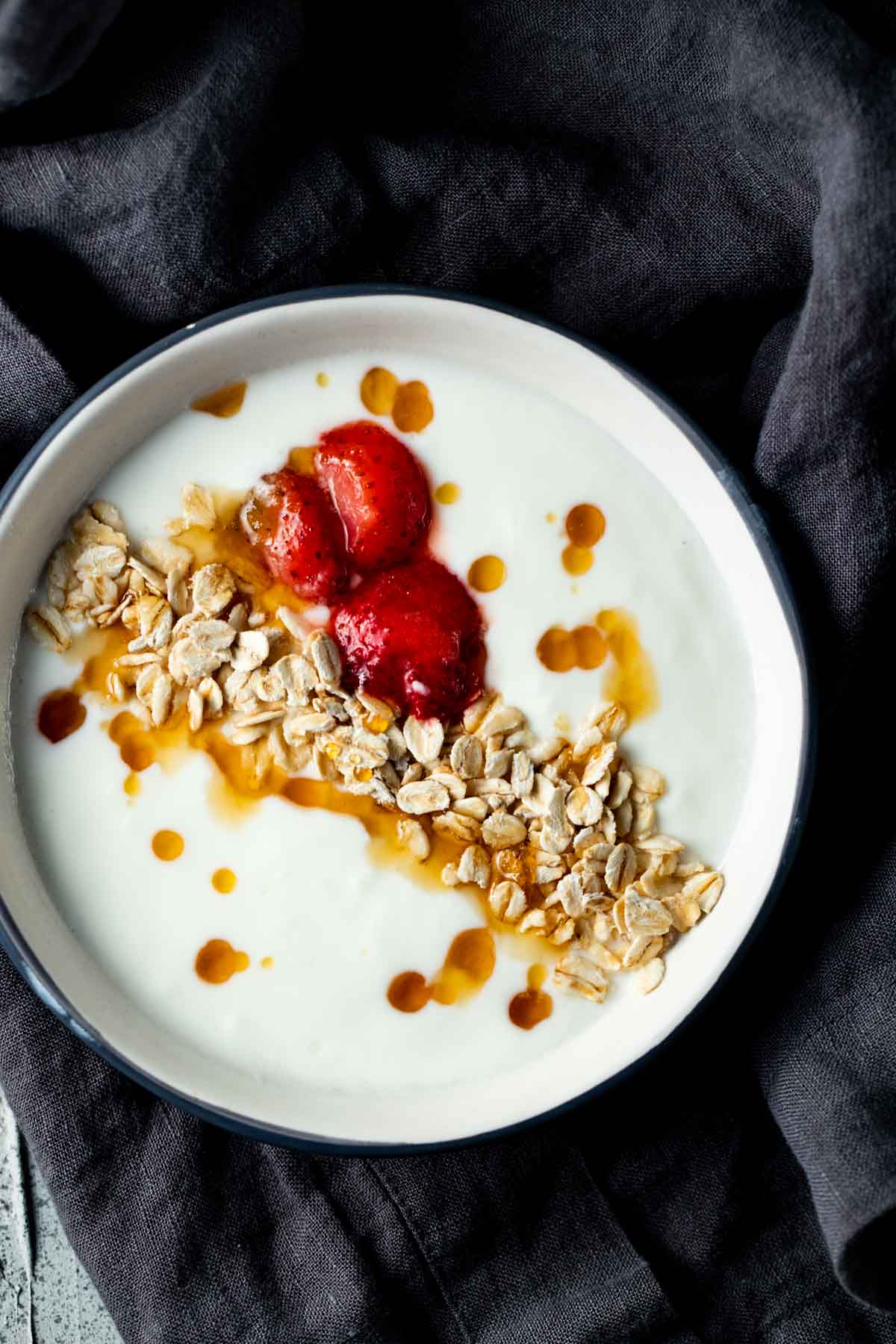 a bowl of yogurt with granola, honey and strawberries on top