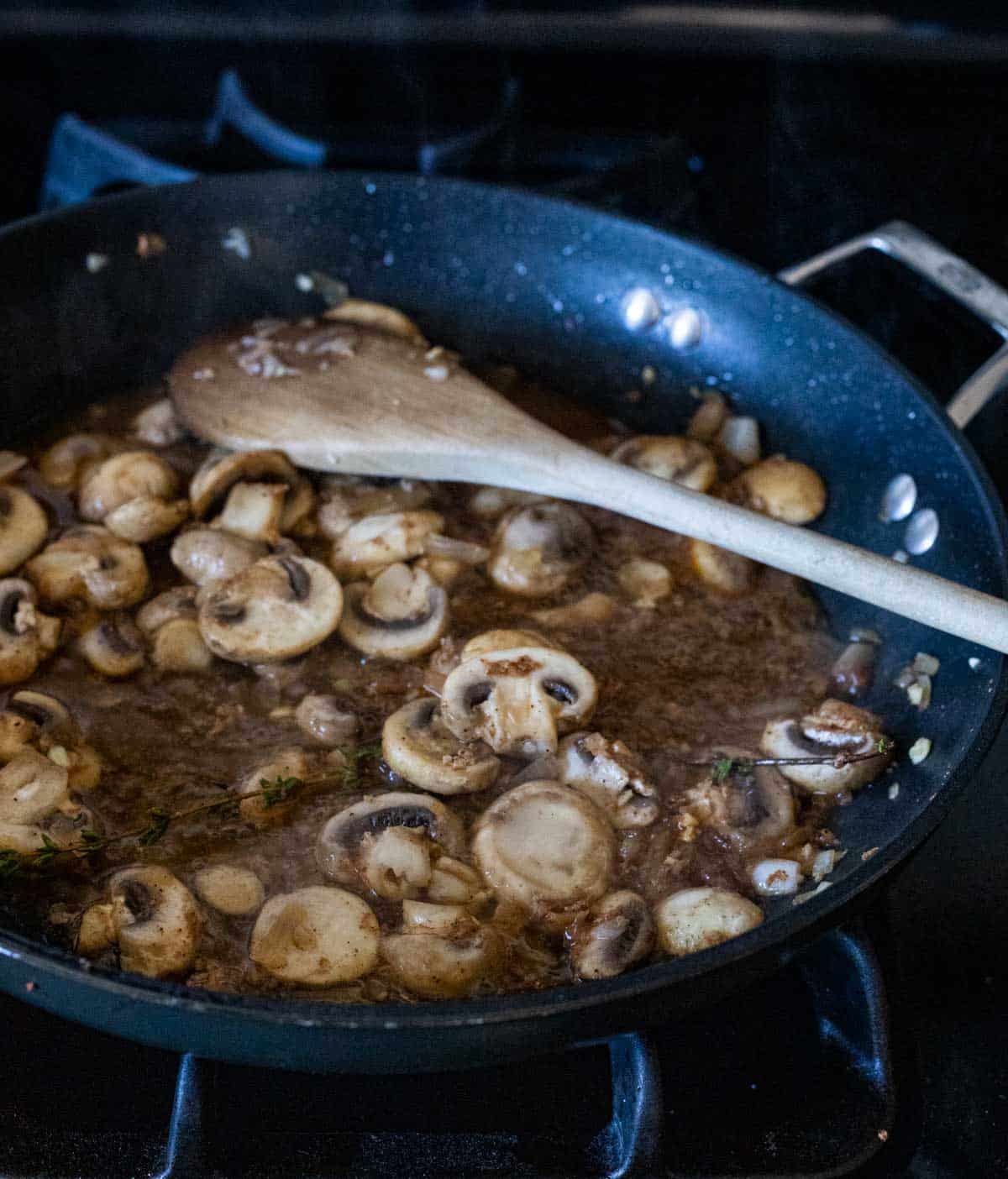 mushrooms sauteed in a skillet with a brown liquid