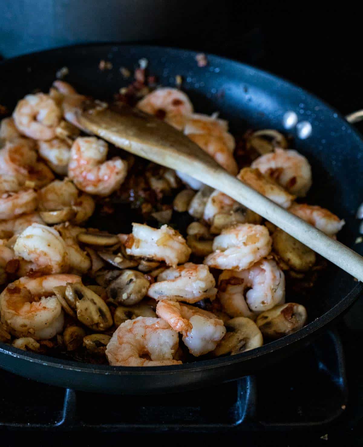 shrimp and mushrooms cooking in a sauce in a skillet