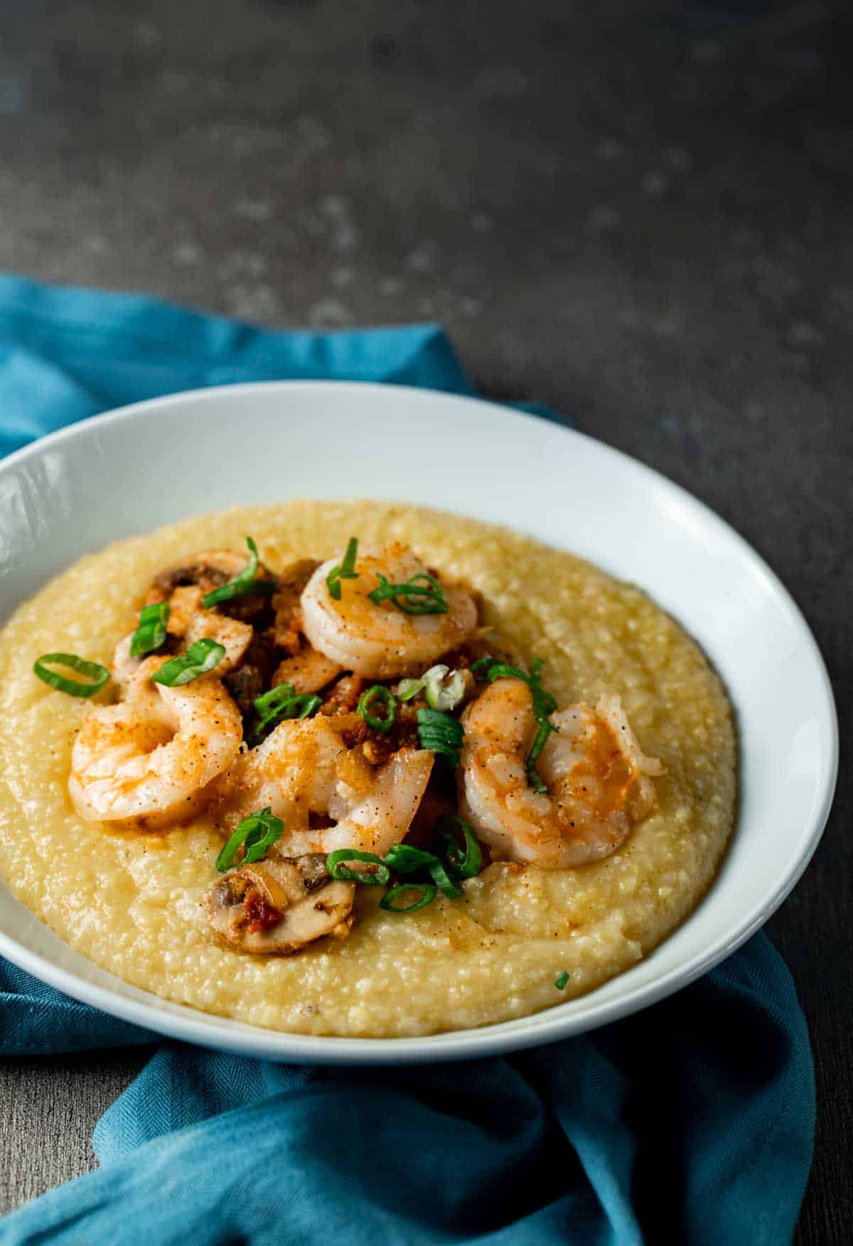 shrimp on top of yellow grits in a white bowl