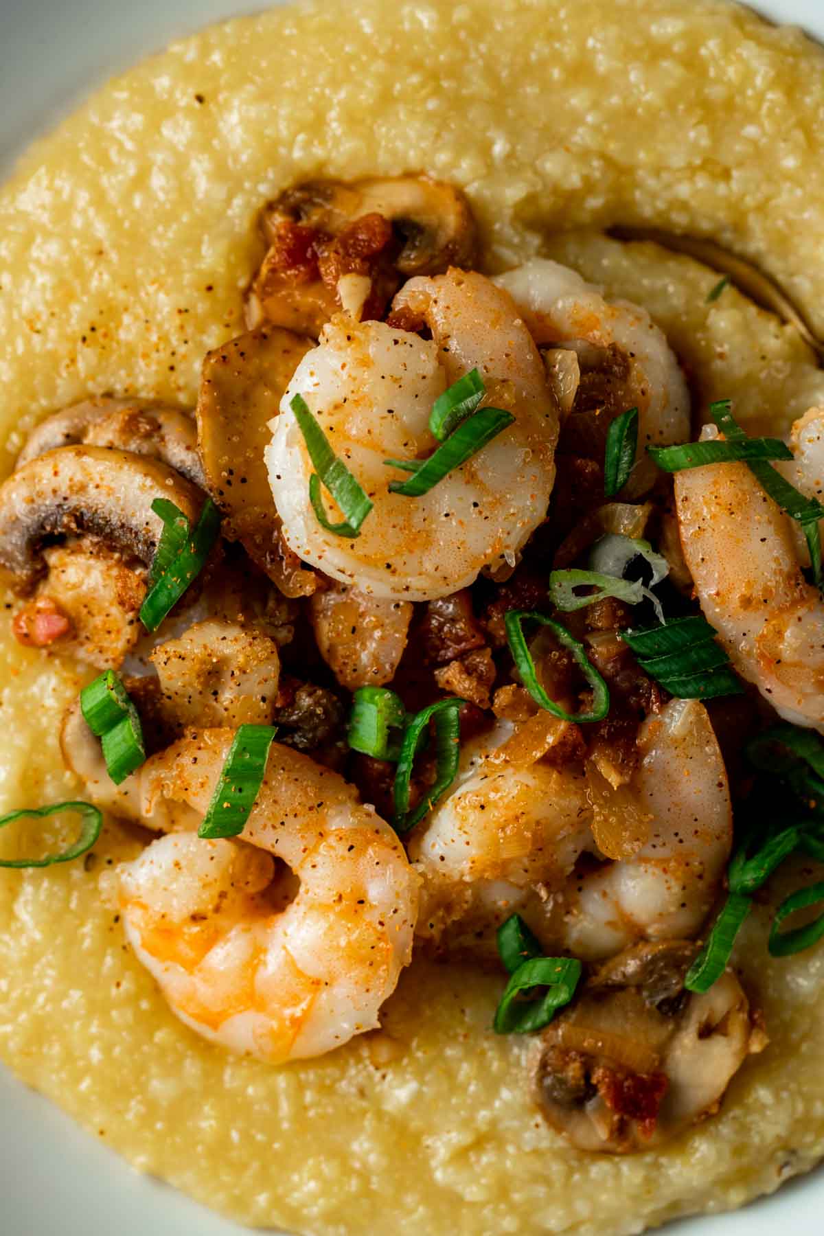 close up of shrimp and pancetta with green onions over polenta