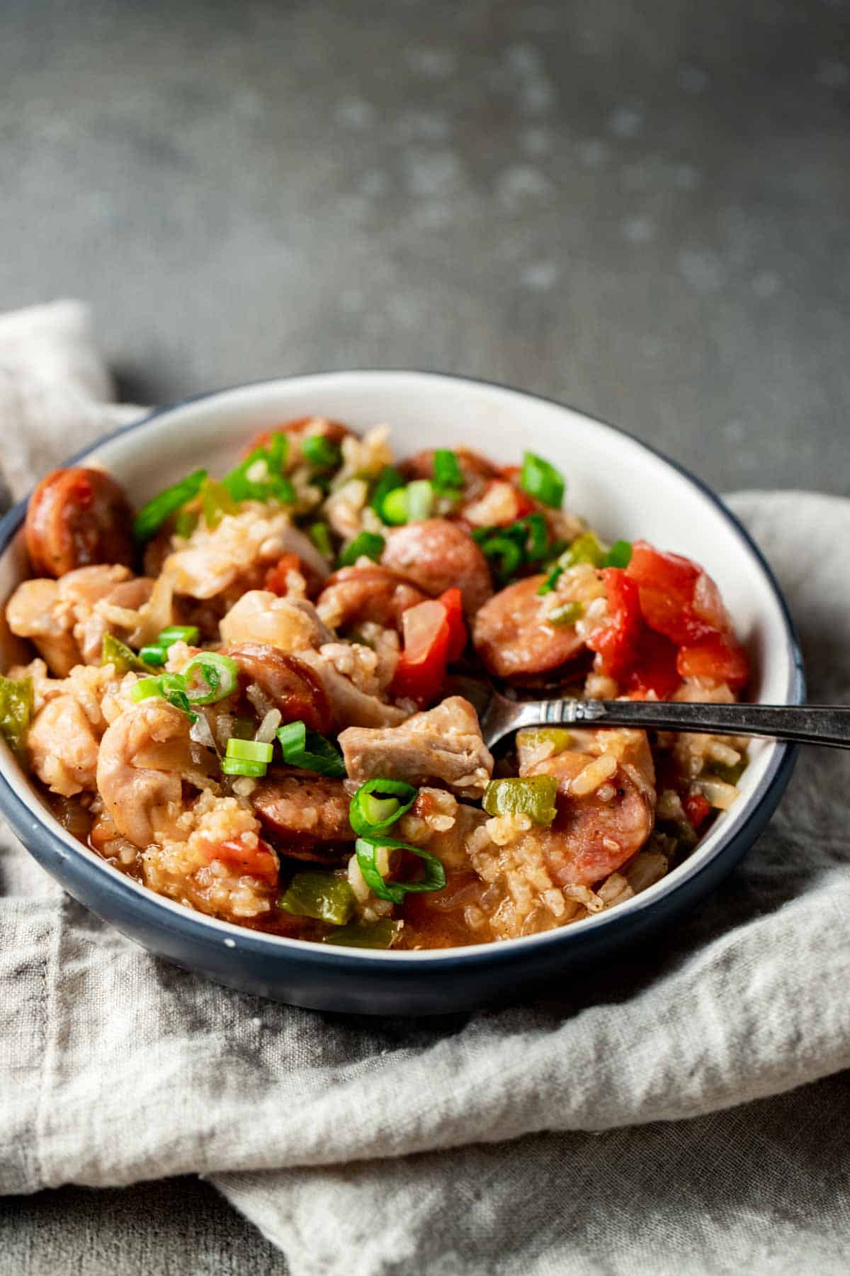 rice in a bowl with a spoon with veggies and sausage
