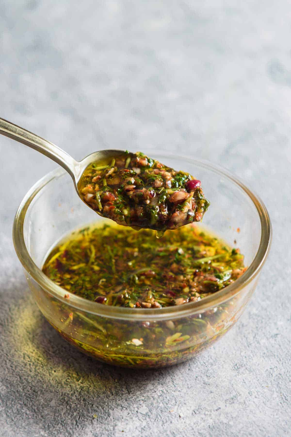 a spoonful of chimichurri over a bowl