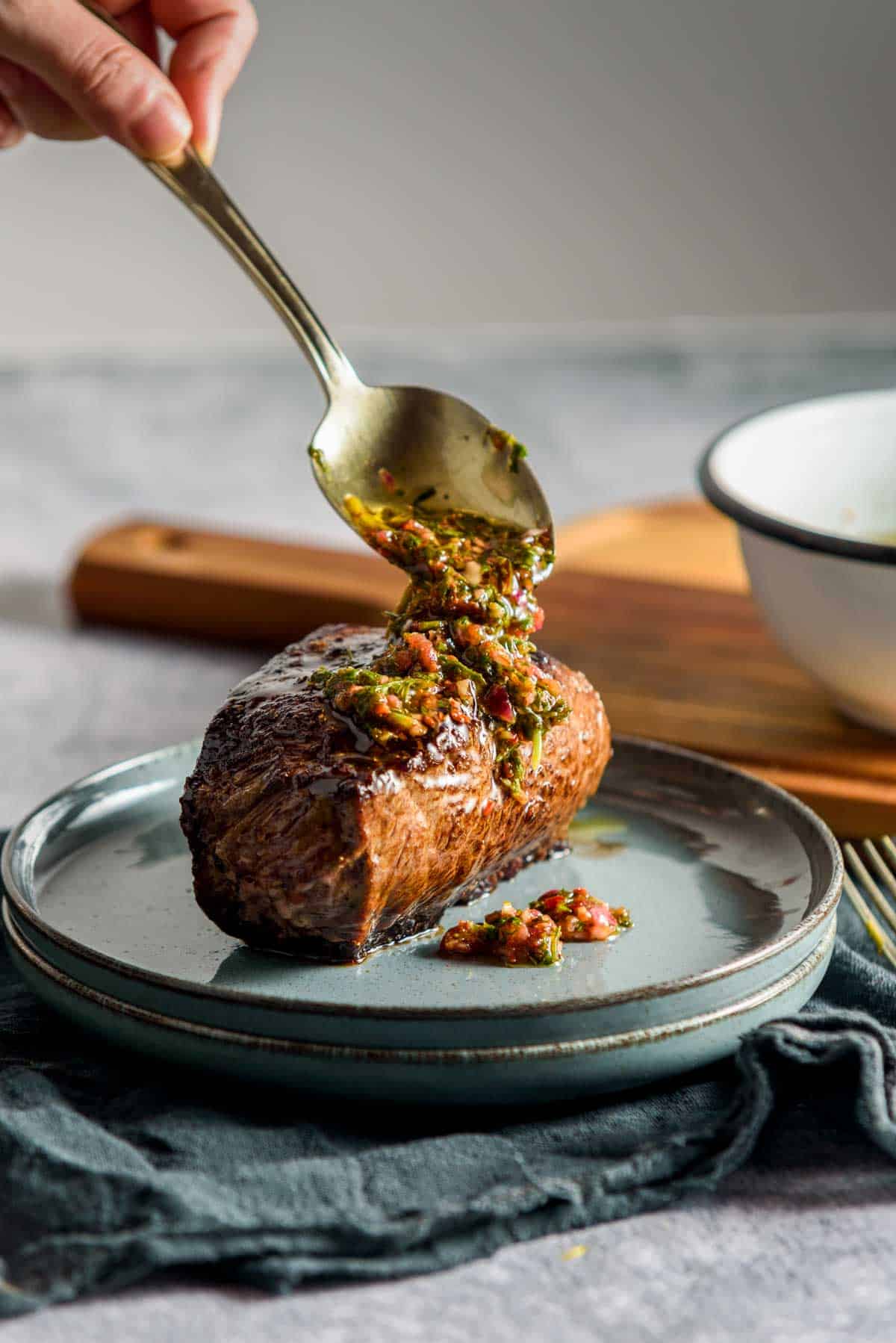 green chimichurri sauce being pours over a steak
