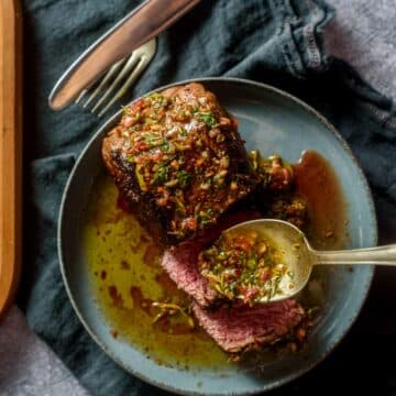 steak on a plate with green herb sauce drizzled on top