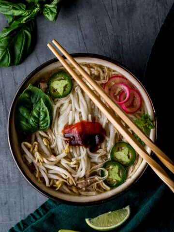 a bowl of vietnamese pho with condiments and chopsticks