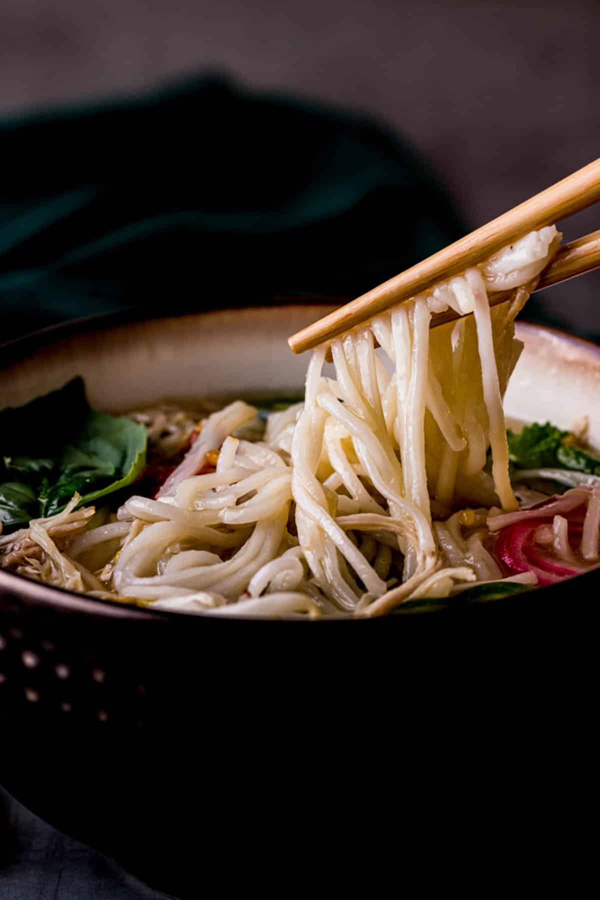 chopsticks pulling noodles out of a bowl of soup