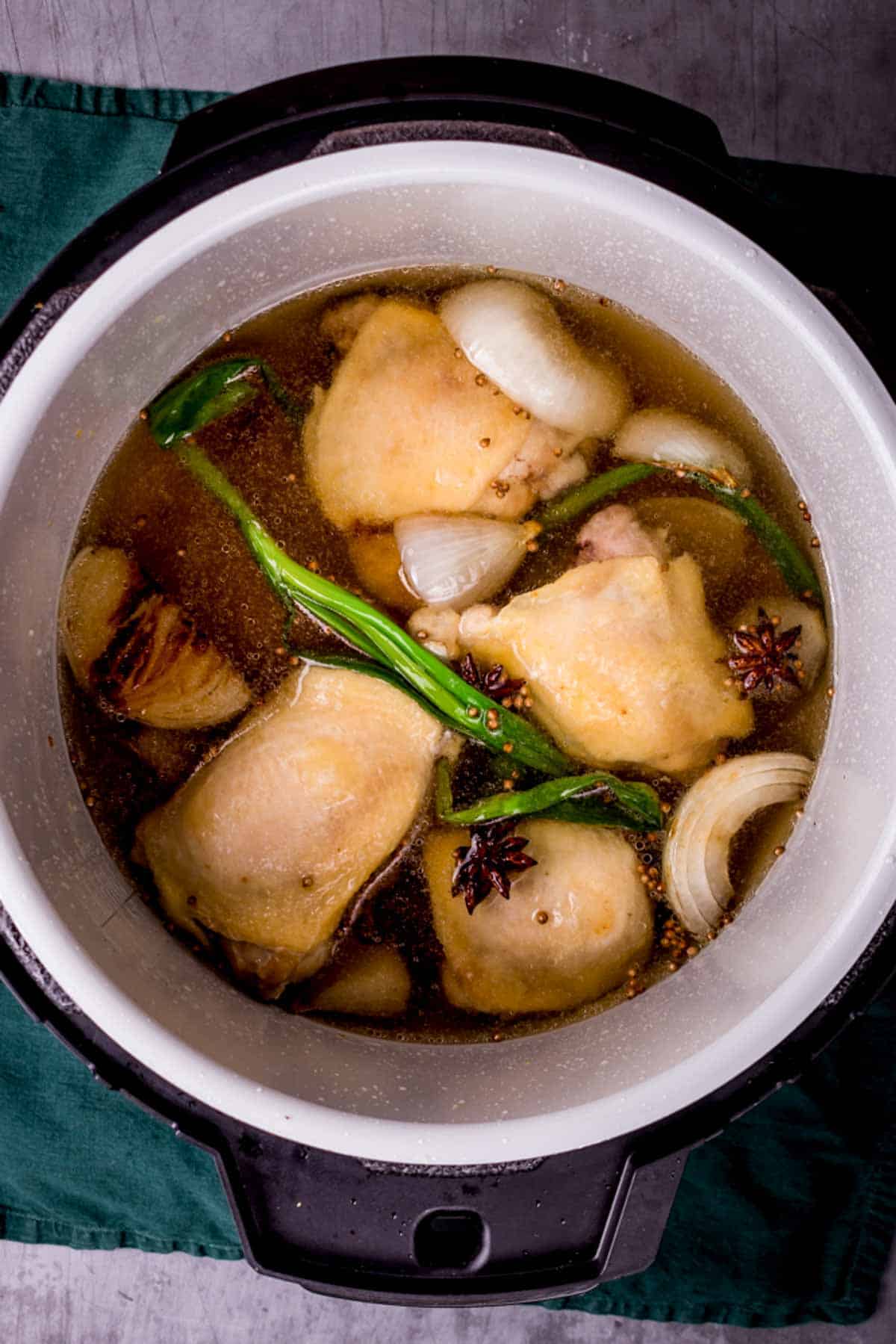 chicken thighs and brown liquid in a pot with green onions