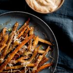 a plate of parmesan truffle fries with orange creamy sauce on the side