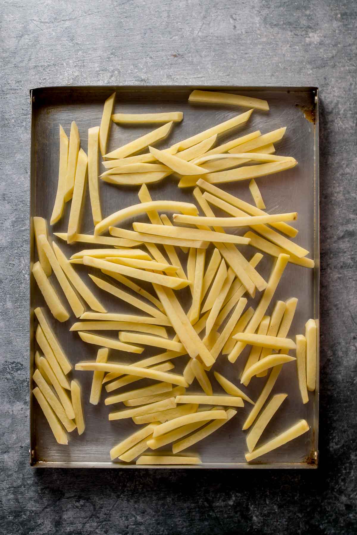Uncooked french fries on a baking sheet