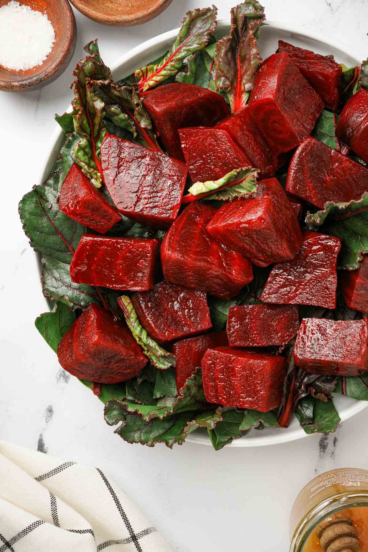 cut up red beets on a plate with greens