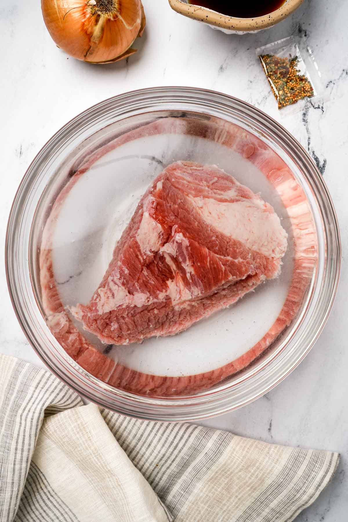 raw corned beef being soaked in water in a bowl