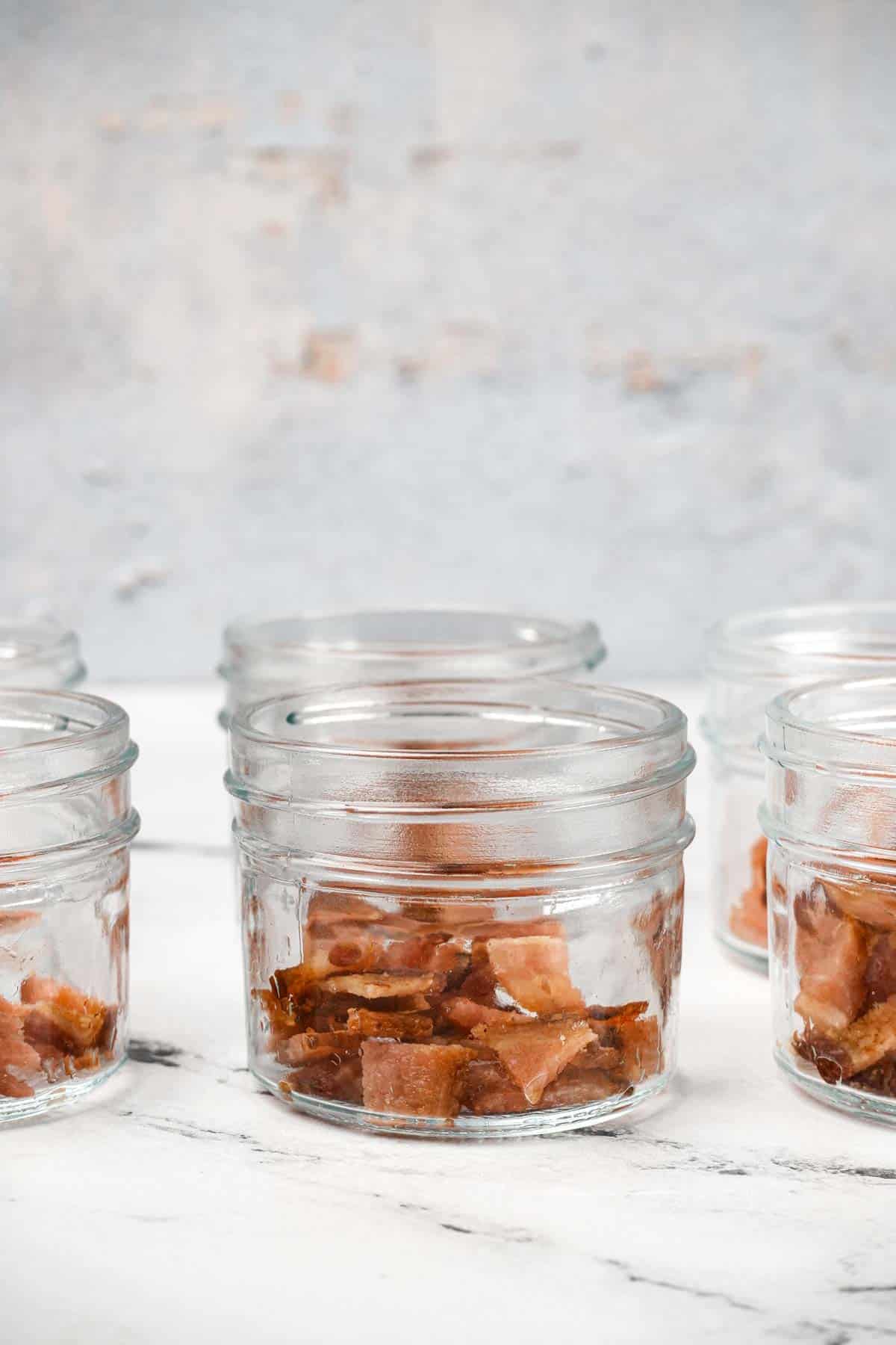 side view of glass jars with bacon pieces in the bottom