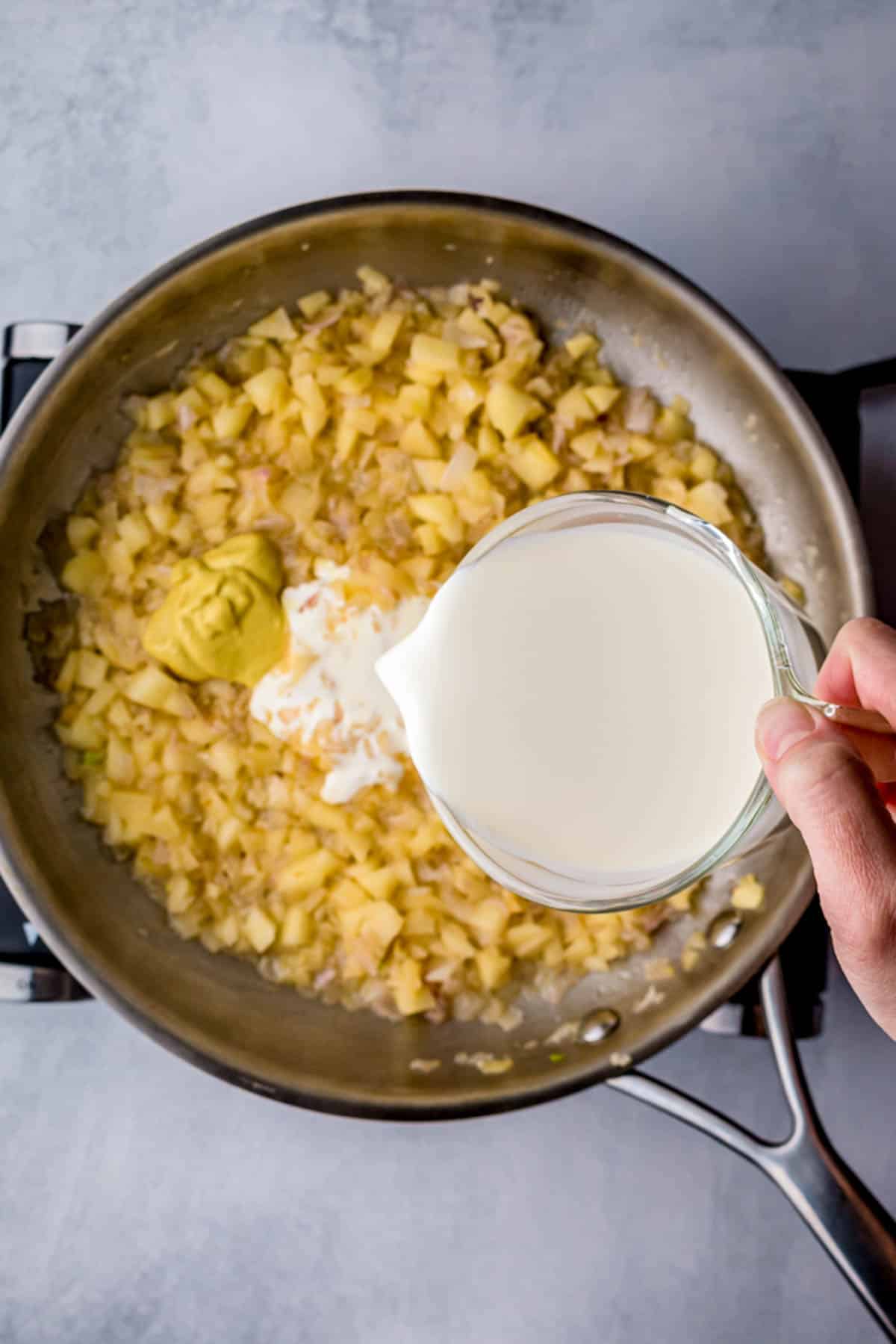 cream being poured into yellow mixture in a skillet