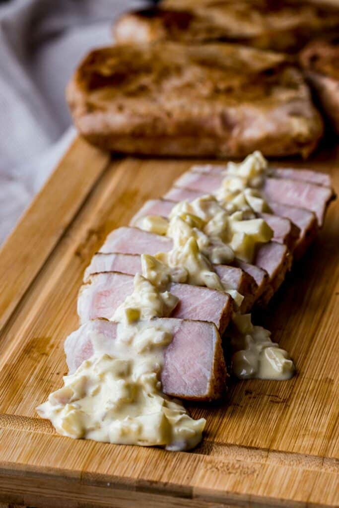 sliced pork chops on a board drizzled with yellow sauce