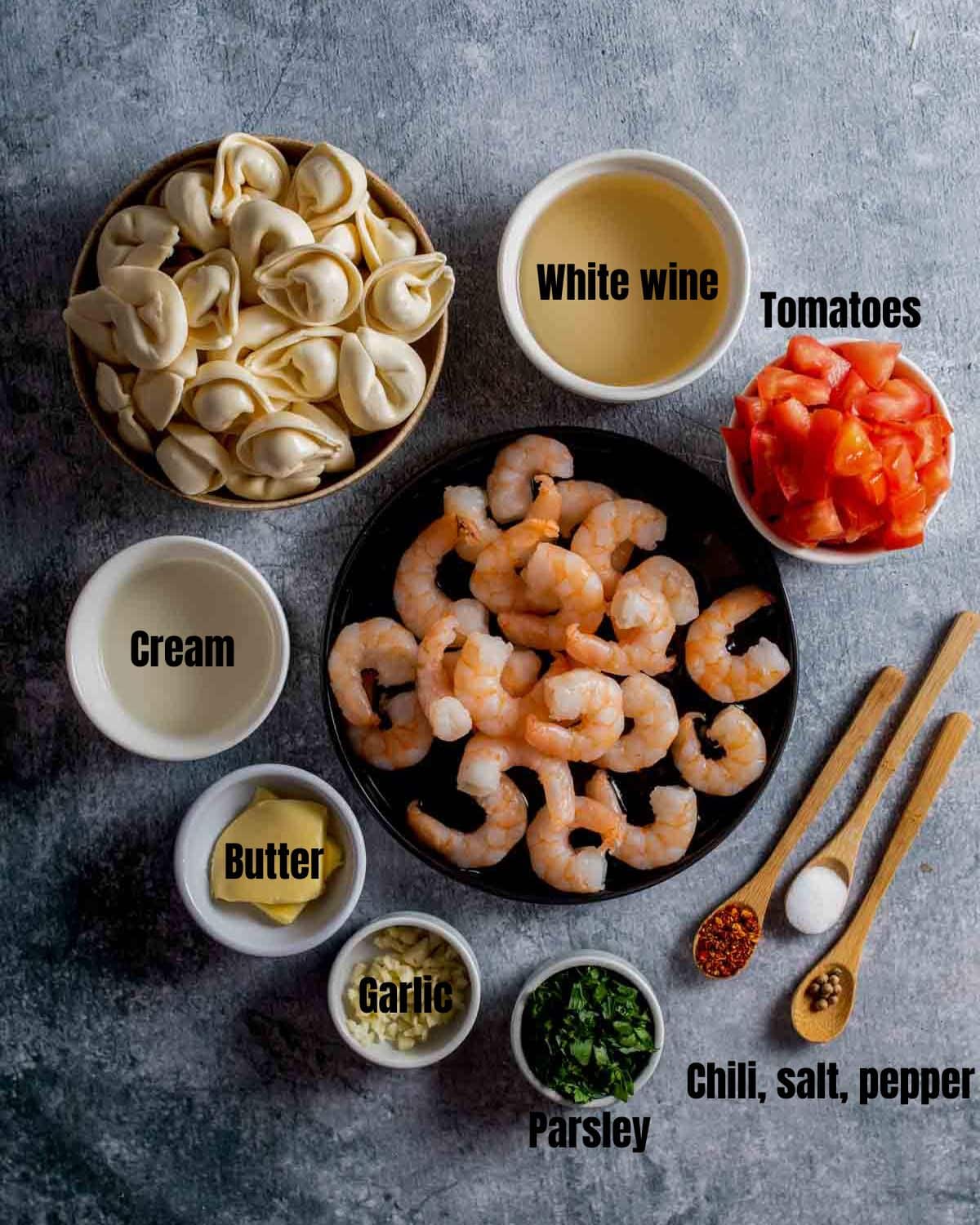 ingredients for shrimp scamp tortellini on a dark board with text overlay