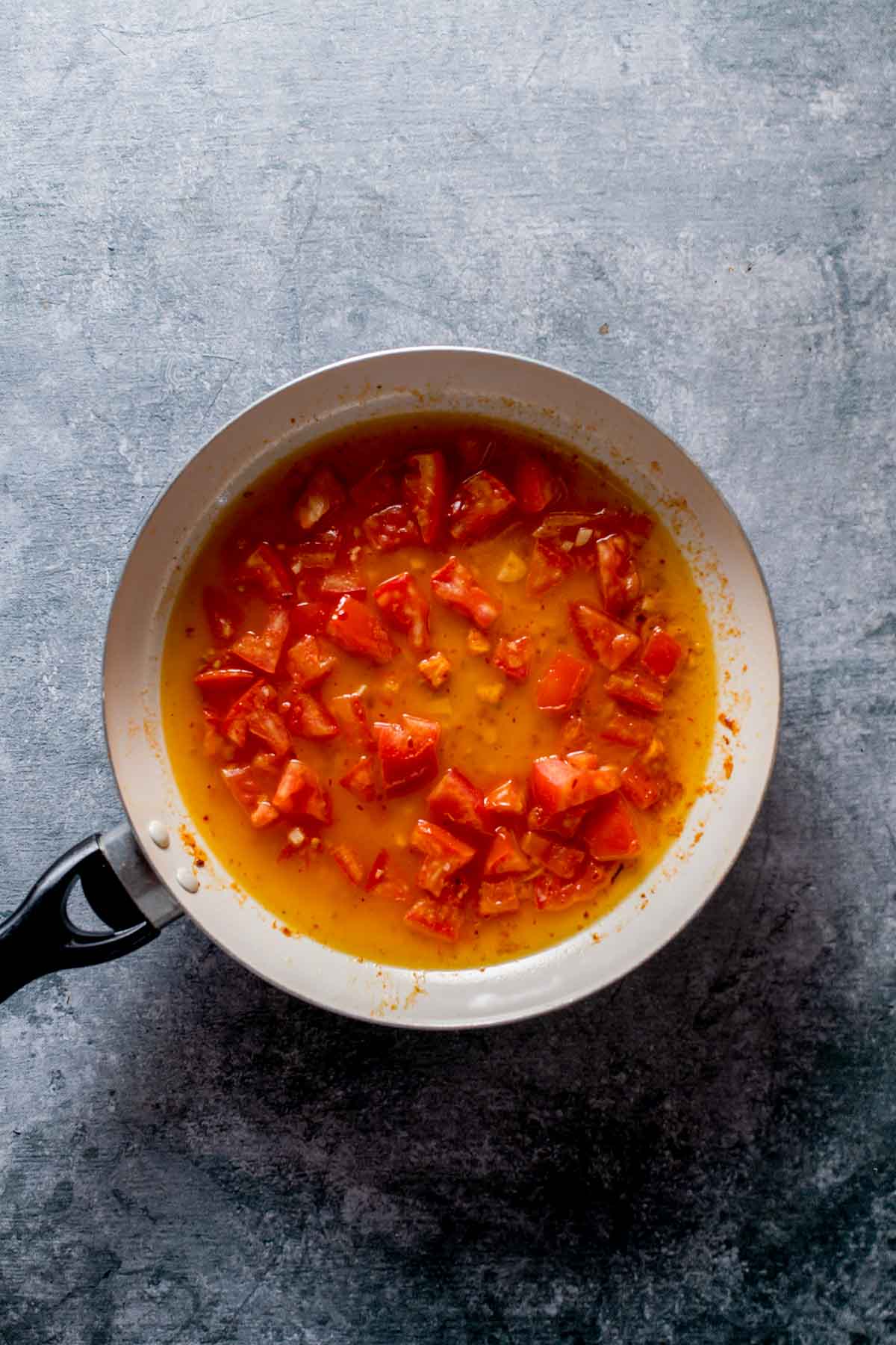 a pan with tomatoes cooking in a liquid
