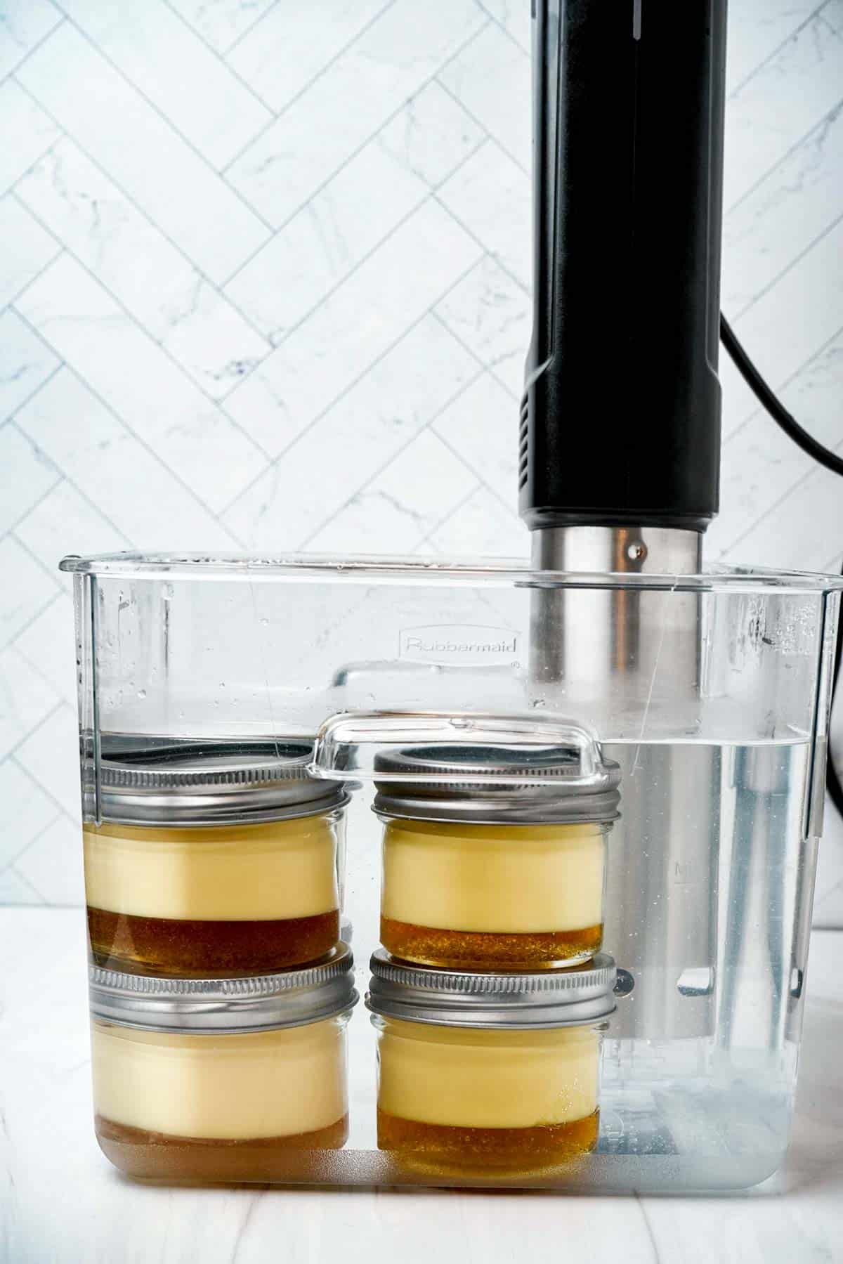glass jars containing custard cooking in a water bath
