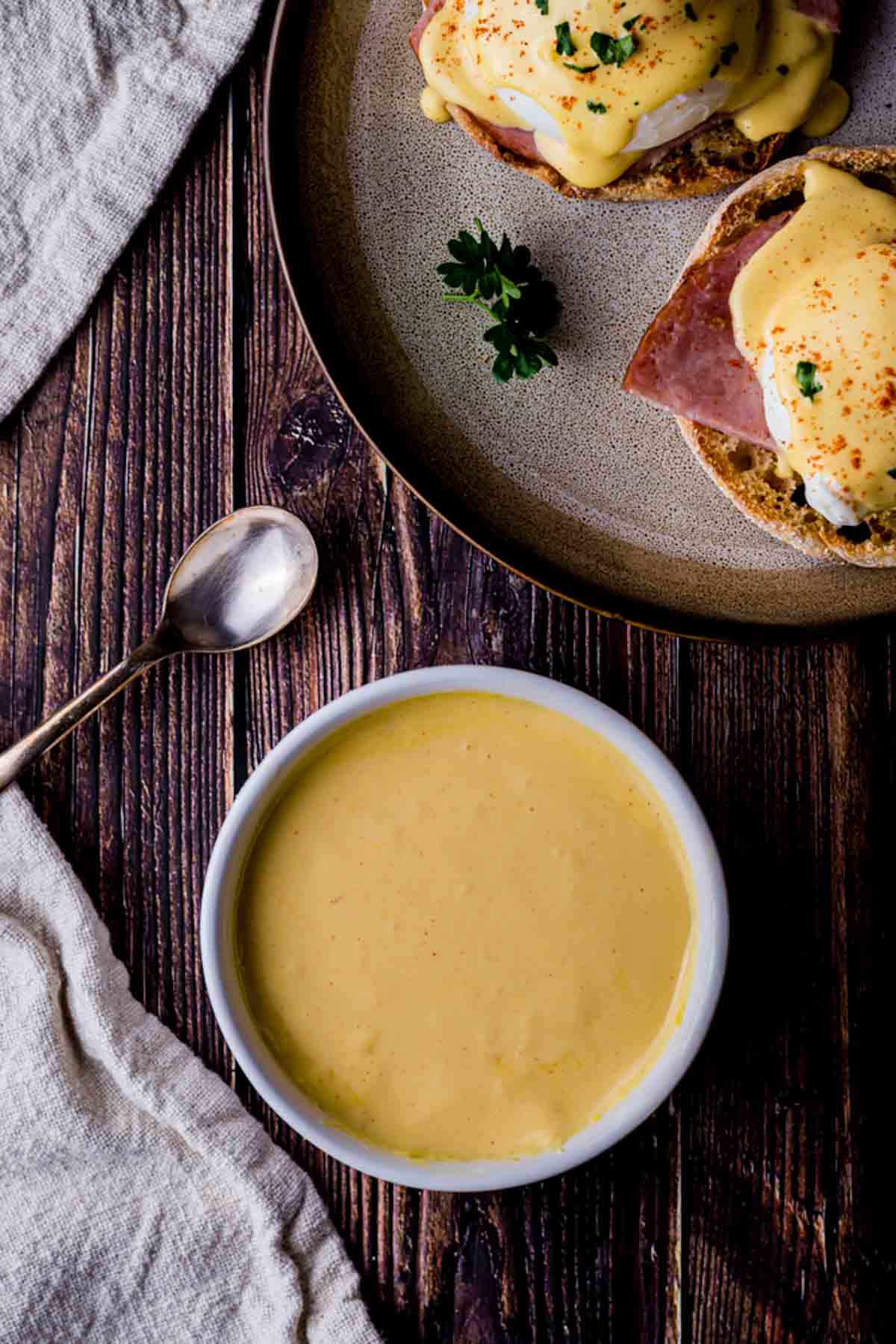 a bowl of yellow sauce with egg benedict on the side
