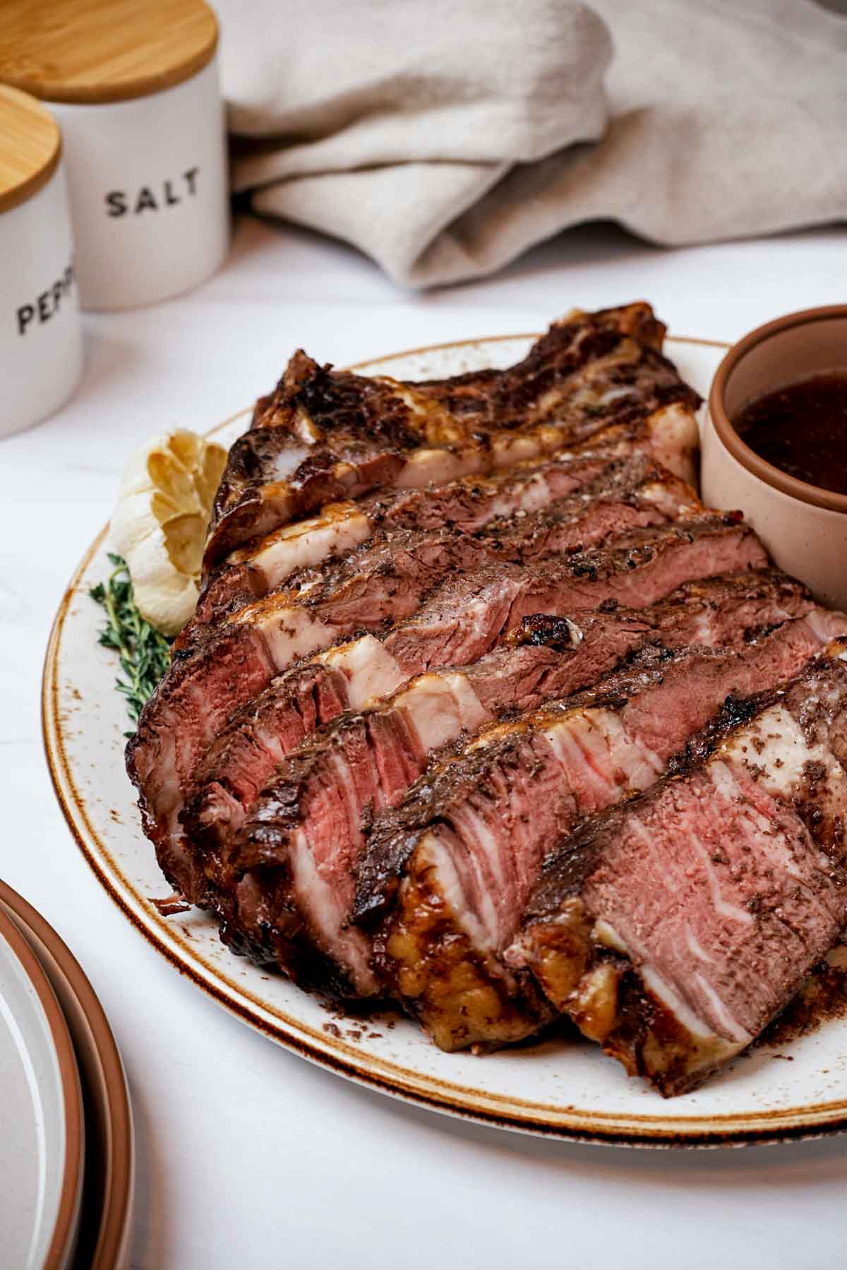 sliced prime rib on a plate with a bowl of sauce