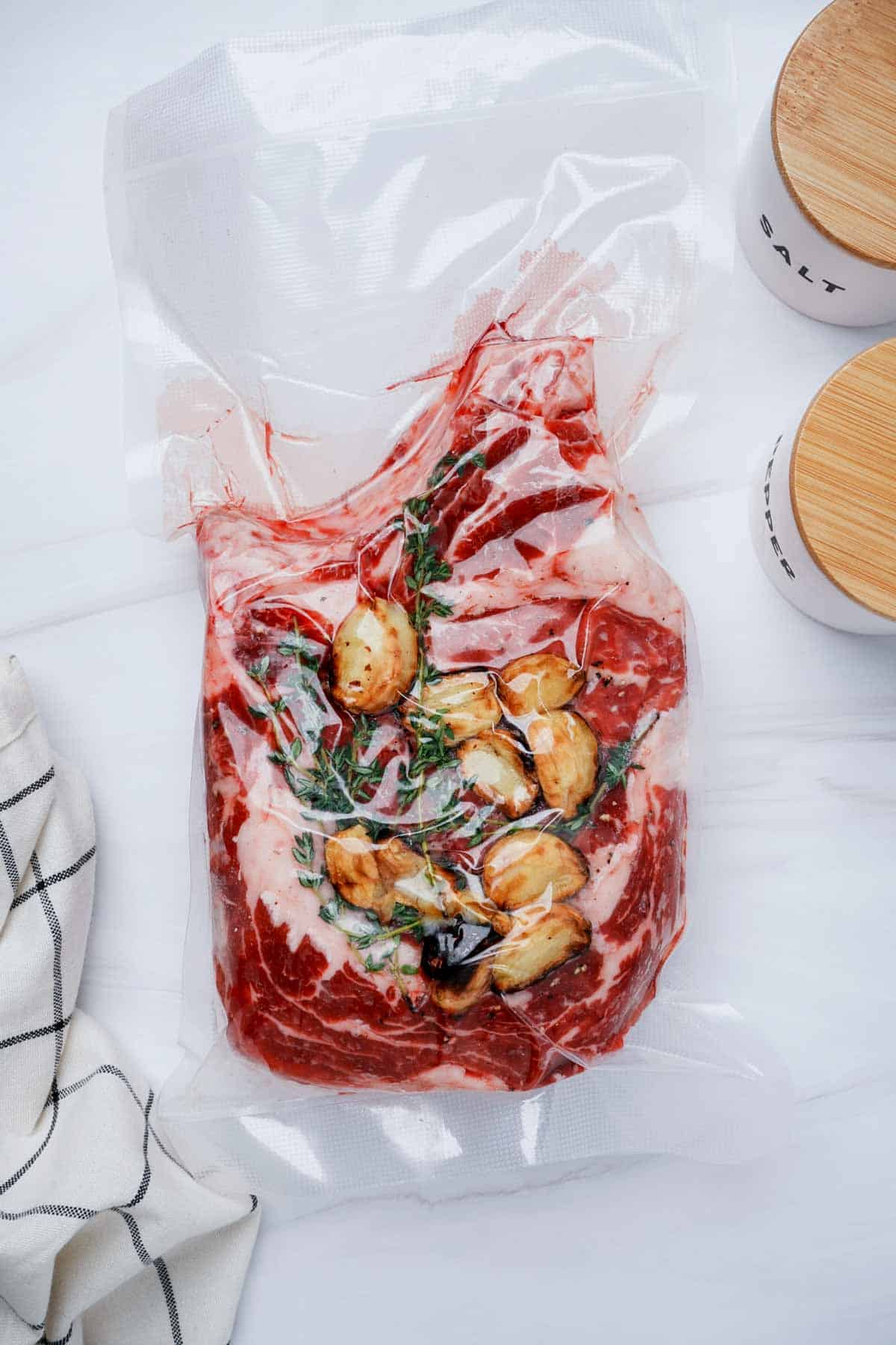 raw beef in a bag with garlic and thyme leaves