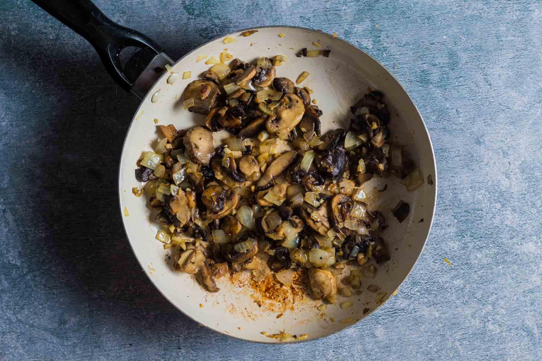 cooked mushrooms and onions with seasonings in a skillet
