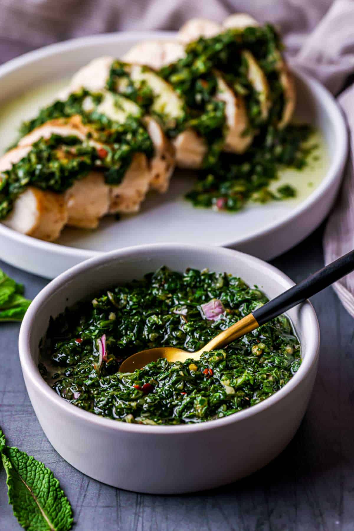 green herb sauce with chicken in the background